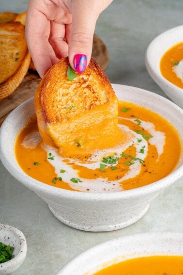 dipping bread into roasted sweet potato soup