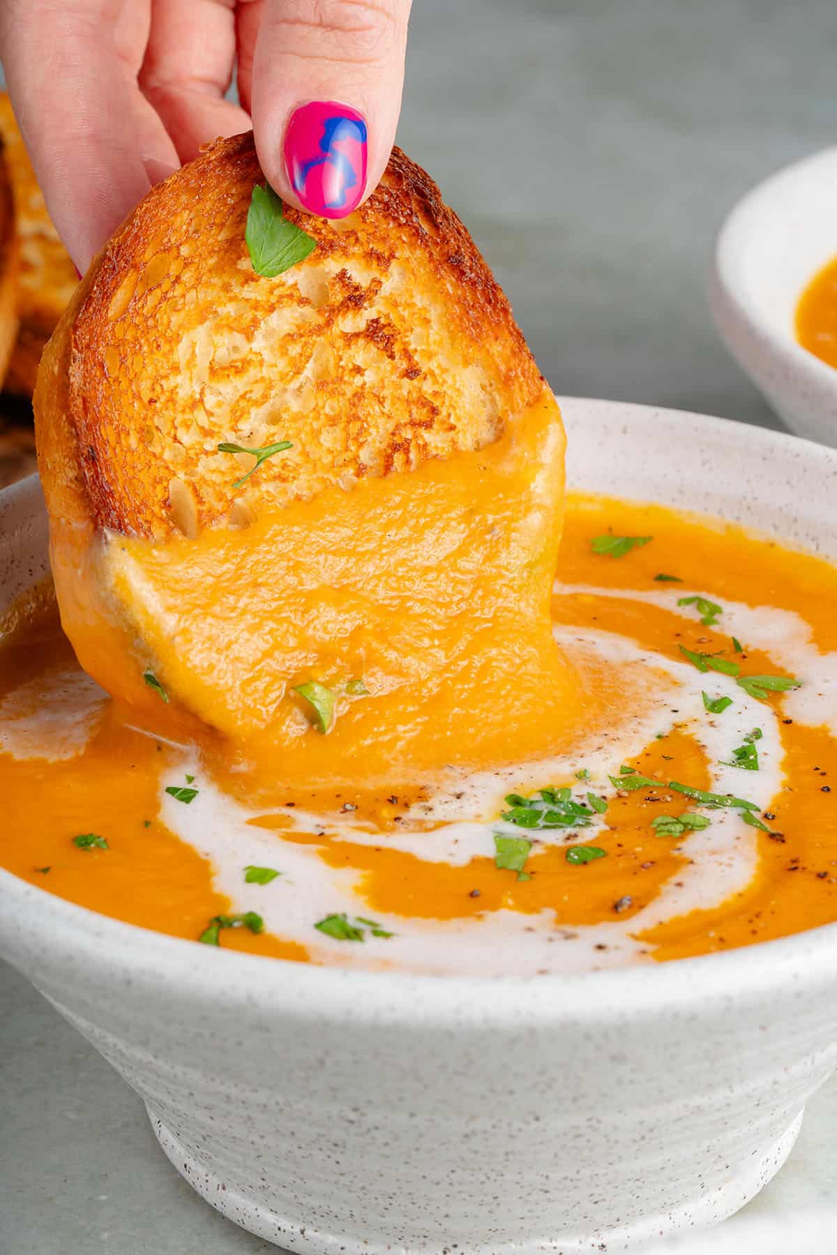 dipping bread into roasted sweet potato soup