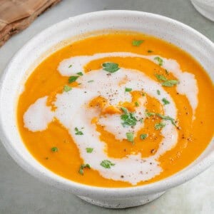 bowl of roasted sweet potato soup topped with coconut milk and parsley