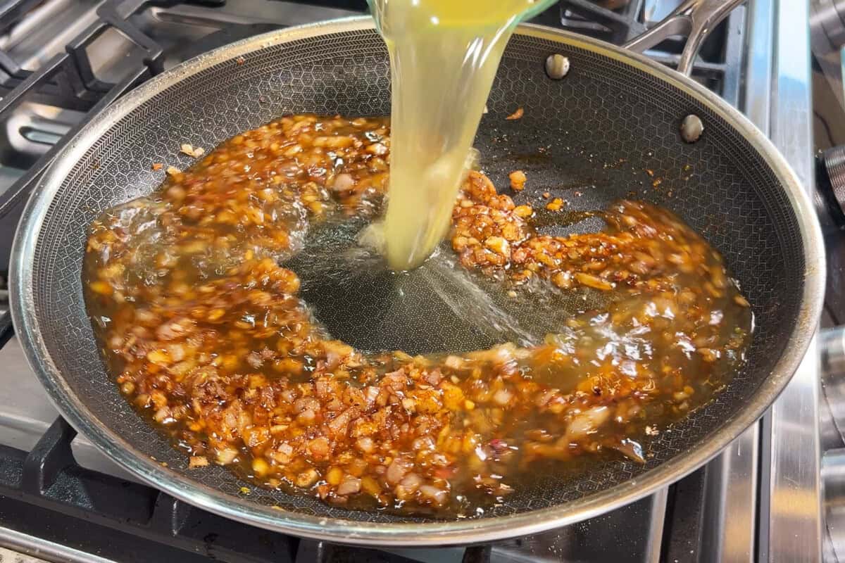 adding broth to the skillet