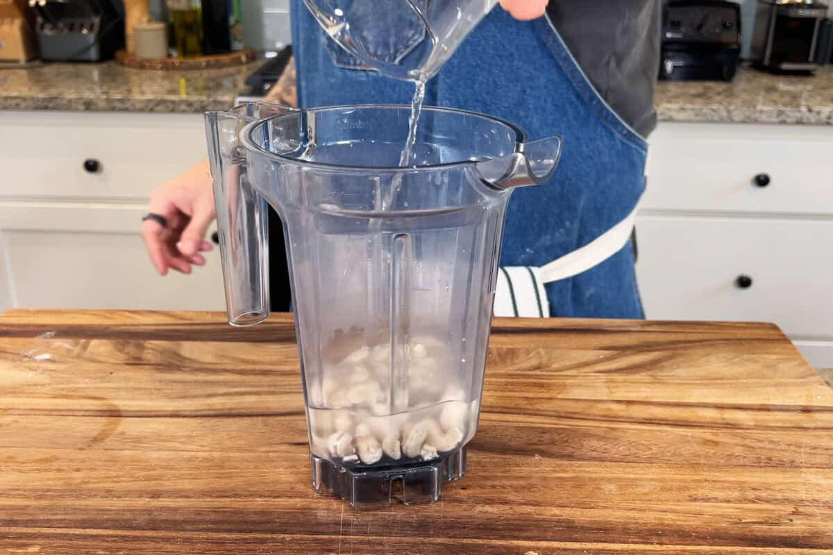 adding soaked cashews to blender