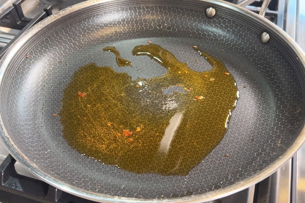 adding sun-dried tomato oil to large skillet