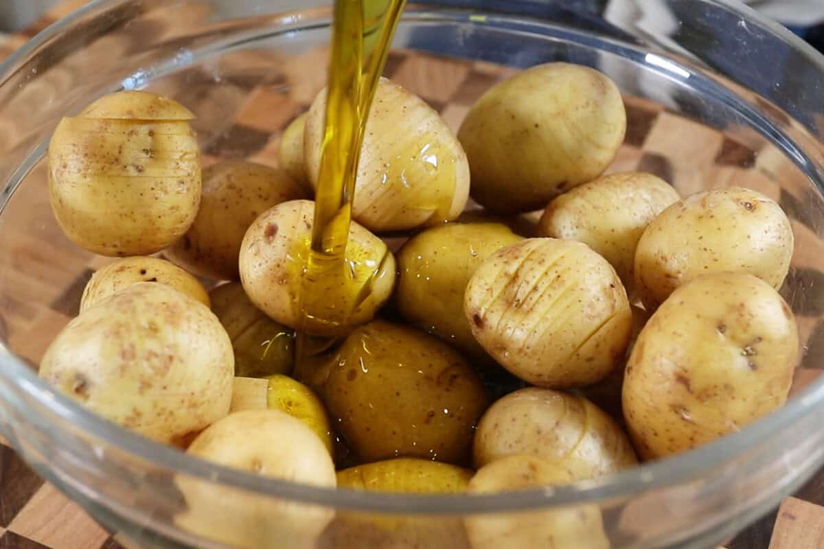 pouring oil over potatoes in a bowl