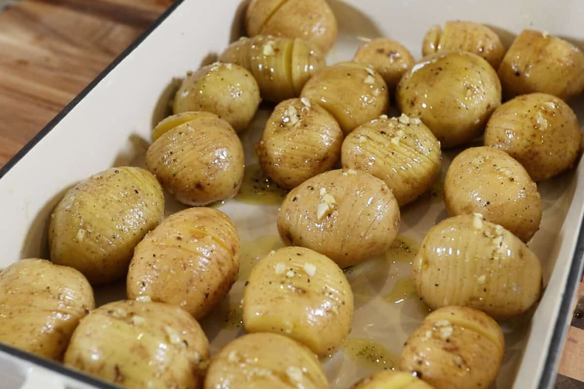 sliced and seasoned potatoes in a baking dish topped with garlic
