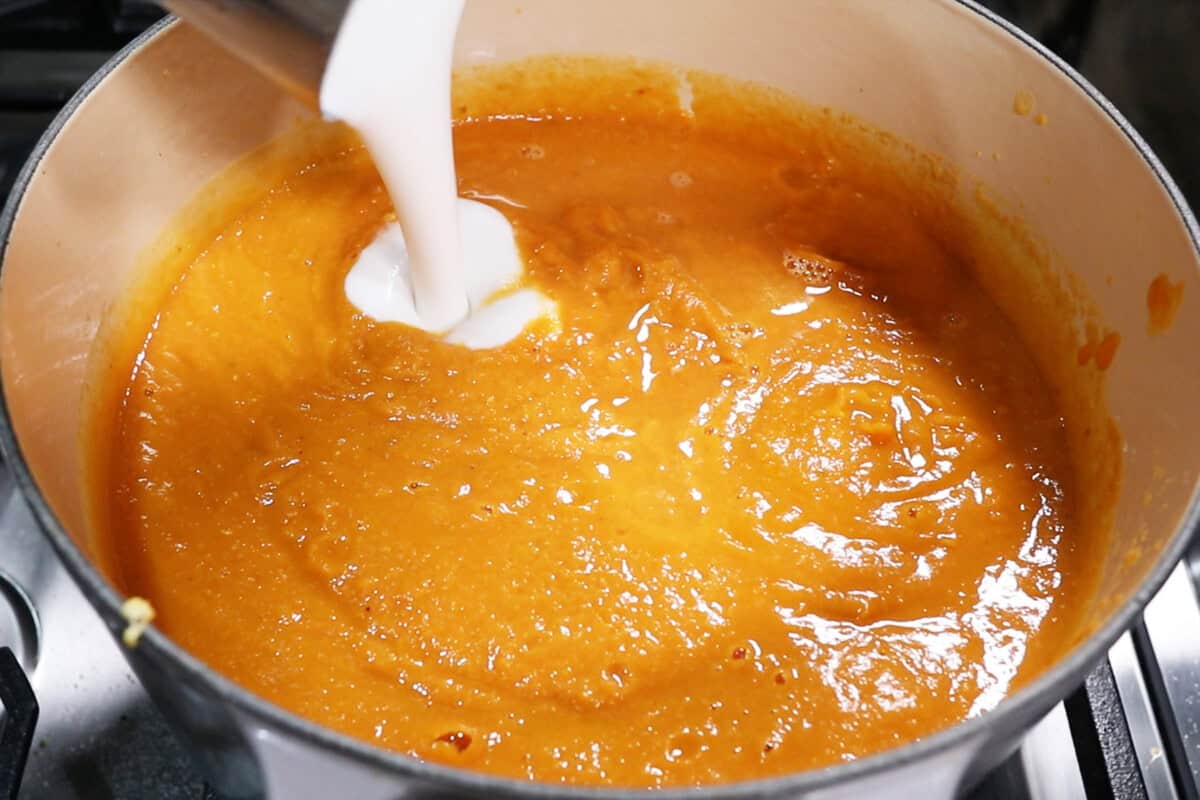 adding coconut milk to roasted sweet potato soup