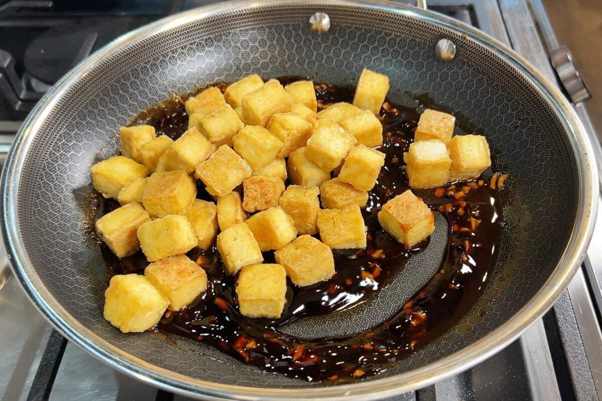 adding tofu to the sauce in a pan