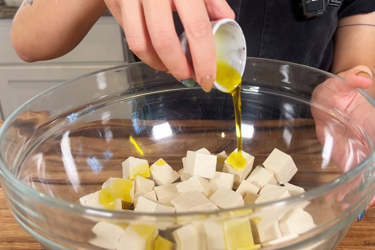 adding oil to tofu in large bowl