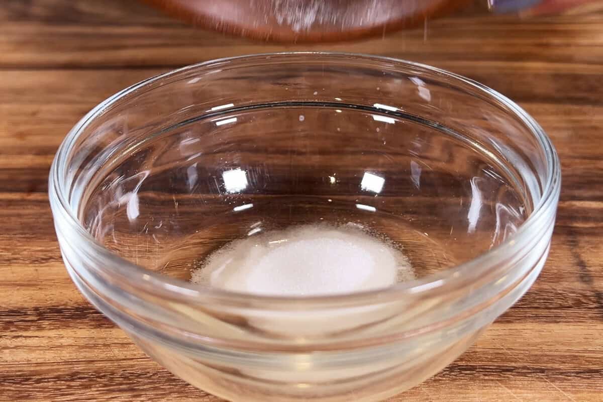 adding sugar to a bowl with rice vinegar