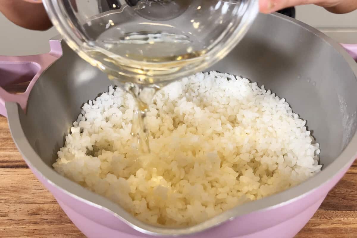 pouring rice vinegar and sugar into rice