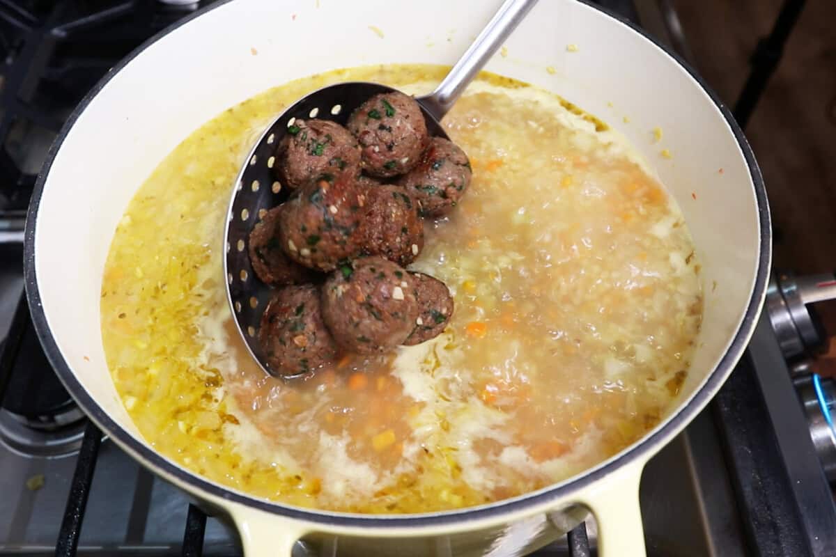 adding cooked meatballs to soup