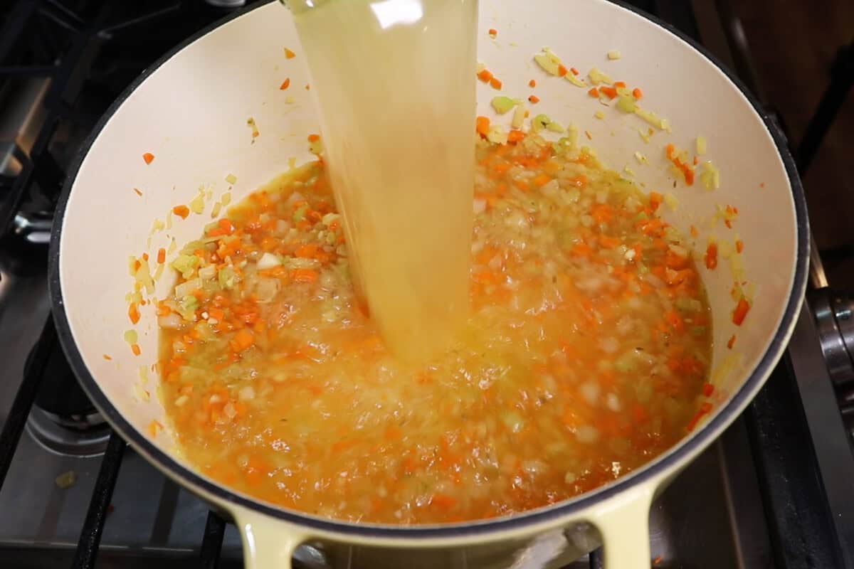 adding broth to large pot