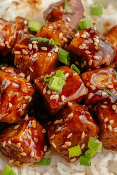 close up of sticky sesame tofu topped with green onions