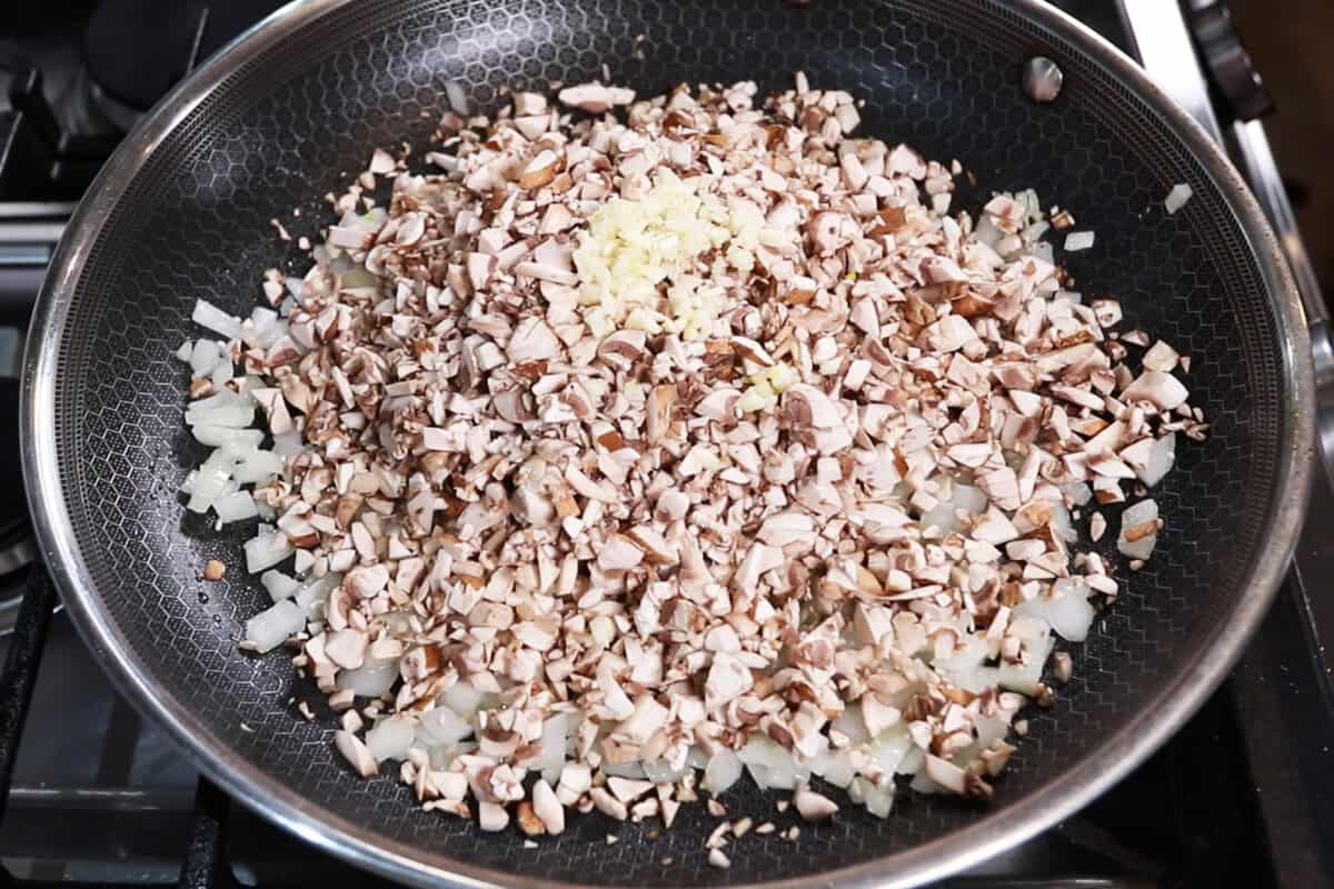 adding mushrooms and garlic to the skillet