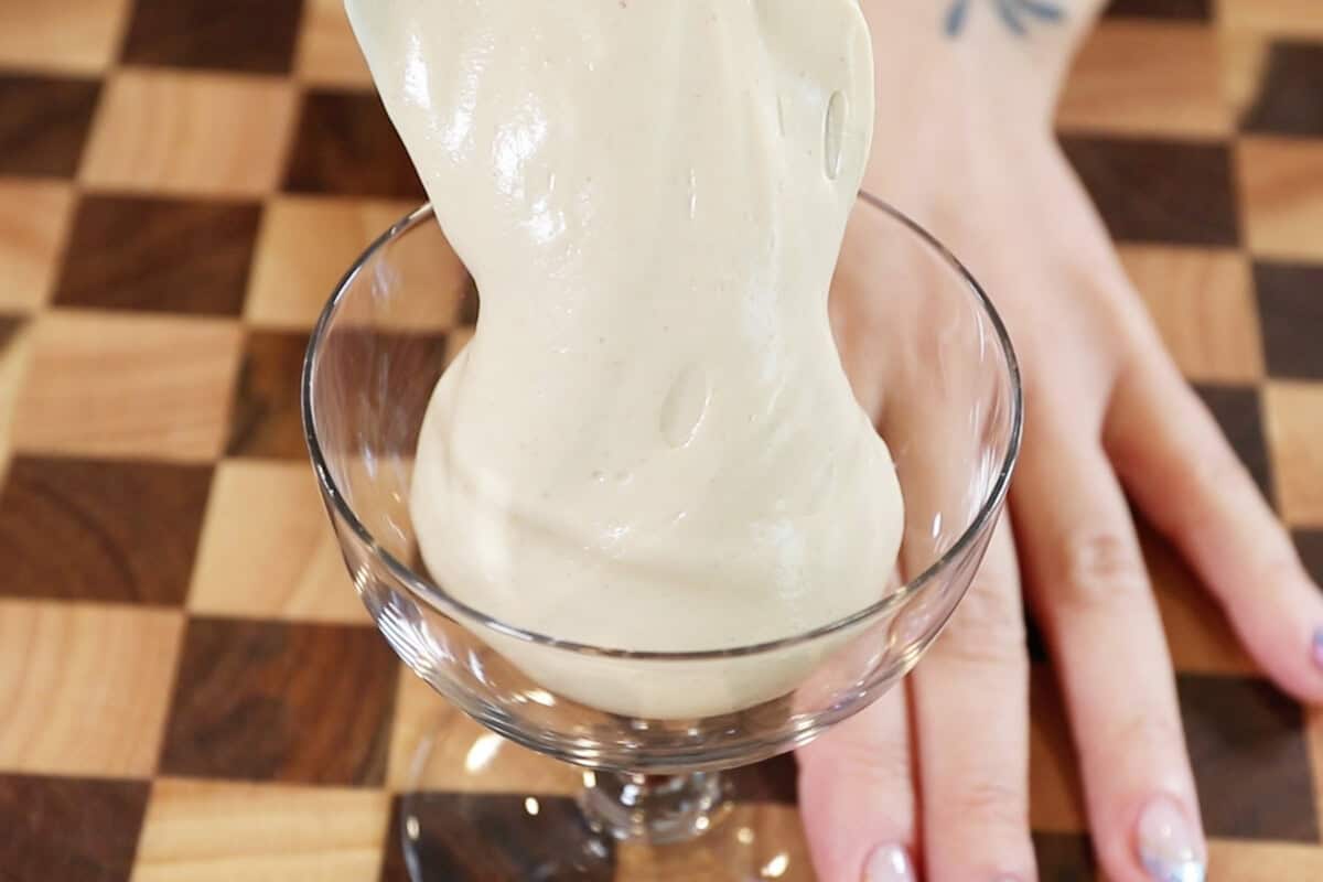 adding peanut butter mousse to a stemmed glass