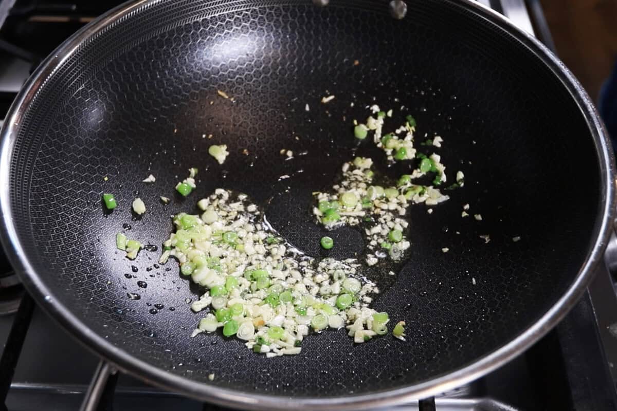 cooking garlic and green onions in a large wok