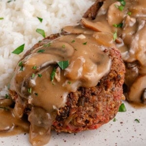 vegan filipino burger steak on a plate topped with mushroom gravy and served with rice