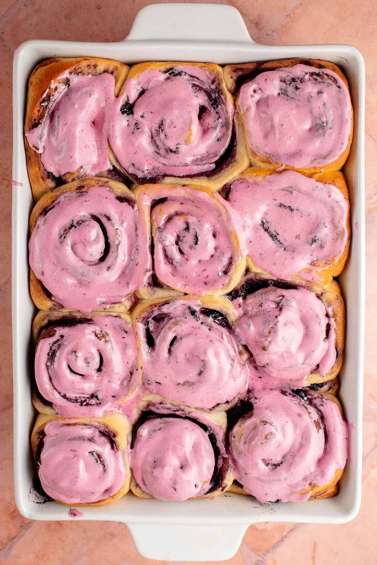 overhead photo of a tray of lemon blueberry rolls with blueberry cream cheese frosting