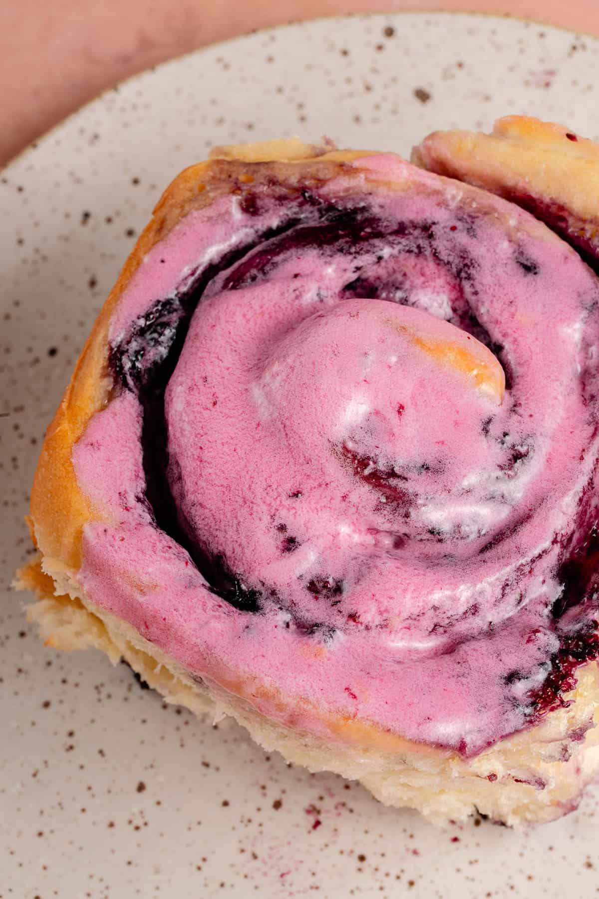 close up of lemon blueberry roll with blueberry cream cheese frosting