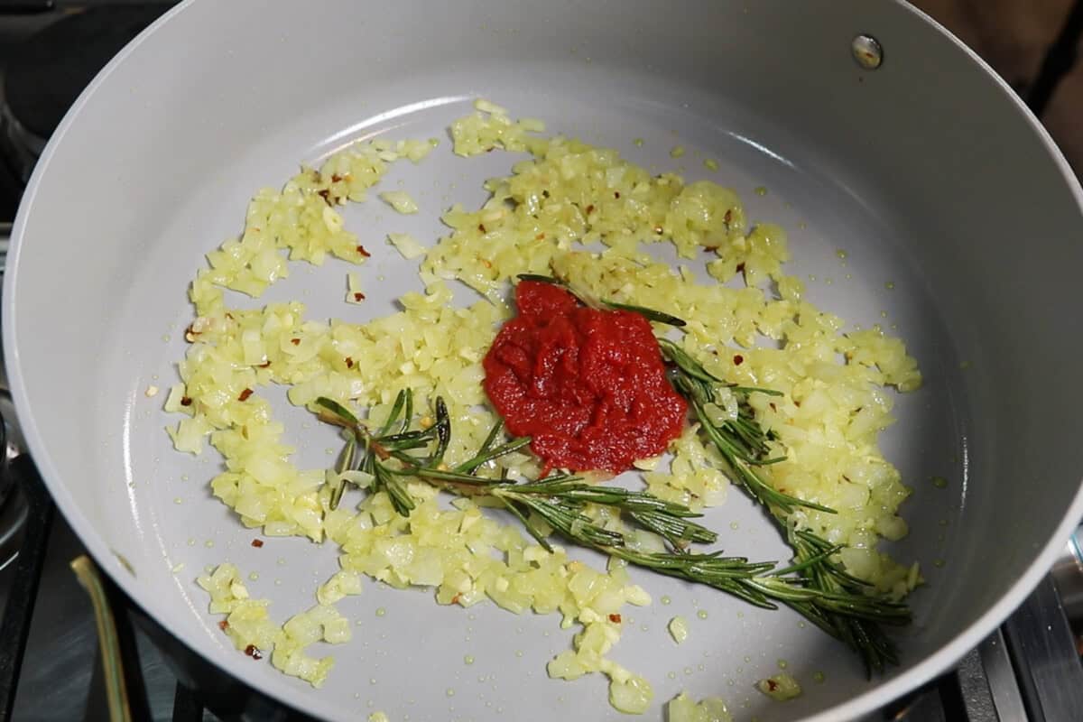 adding tomato paste to the dutch oven