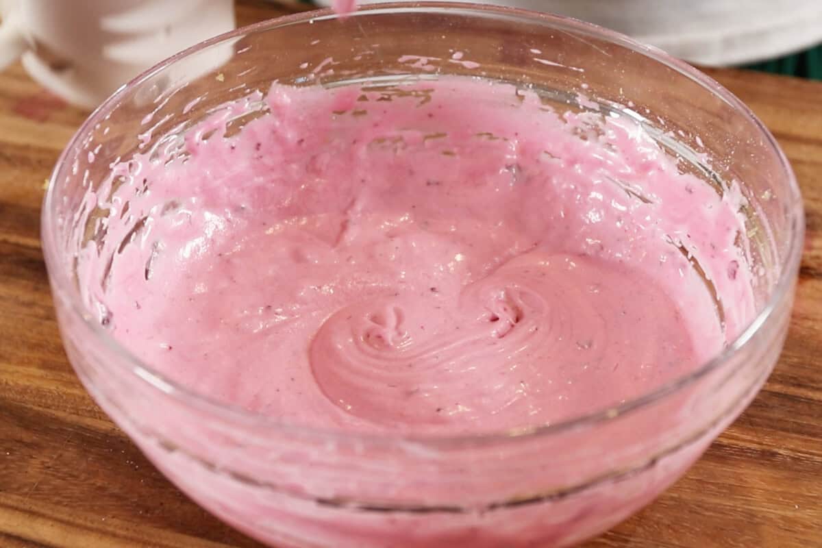 mixing ingredients in a glass bowl for blueberry cream cheese frosting