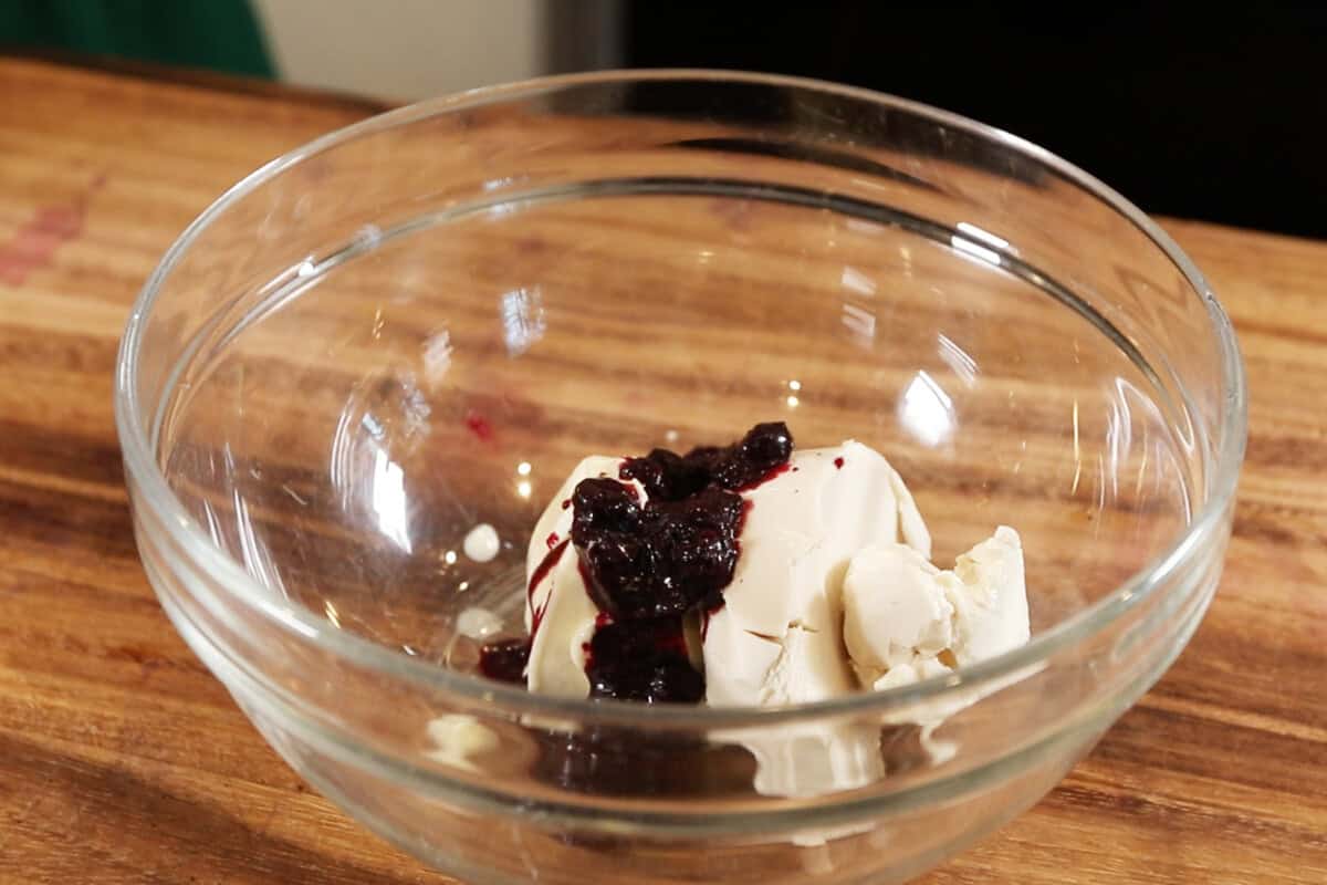 mixing ingredients in a glass bowl for blueberry cream cheese frosting