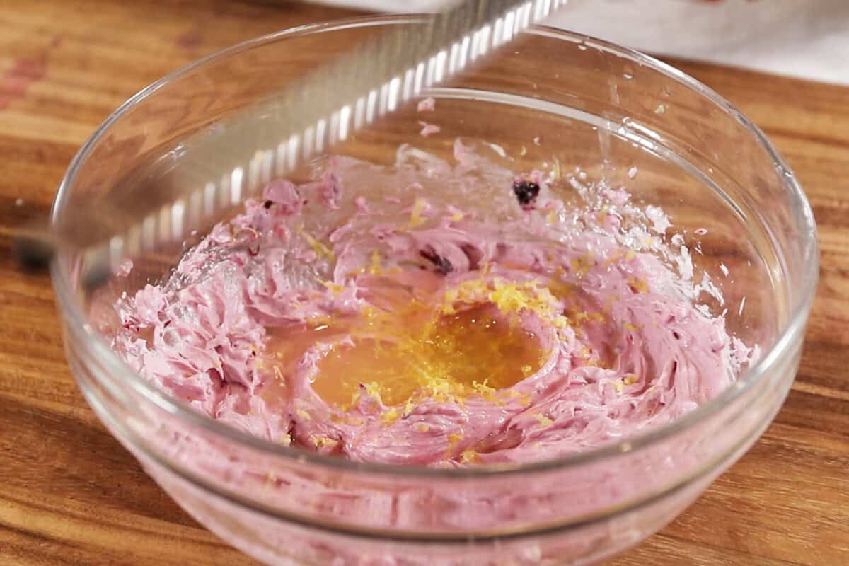 mixing ingredients in a glass bowl for blueberry cream cheese frosting