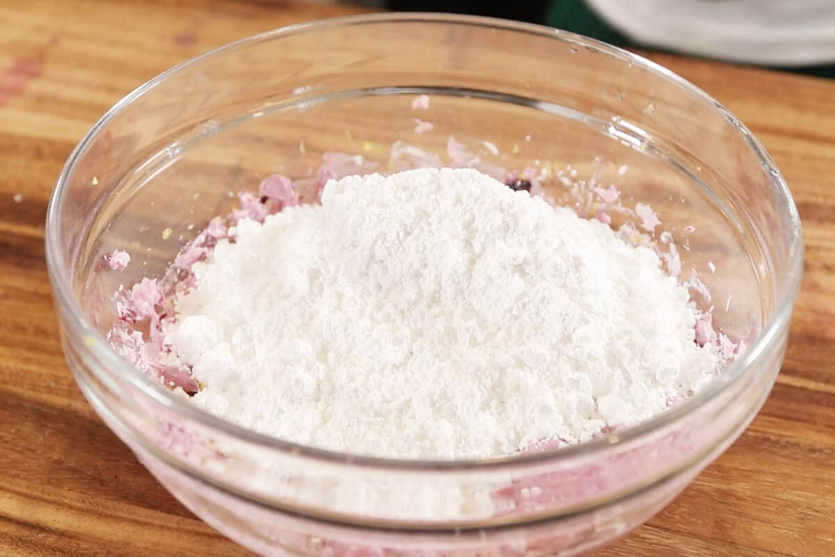 adding powdered sugar to blueberry cream cheese frosting
