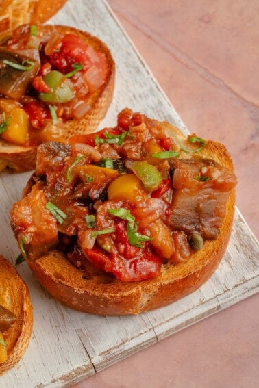 Eggplant Caponata on toasted bread on top of white serving tray