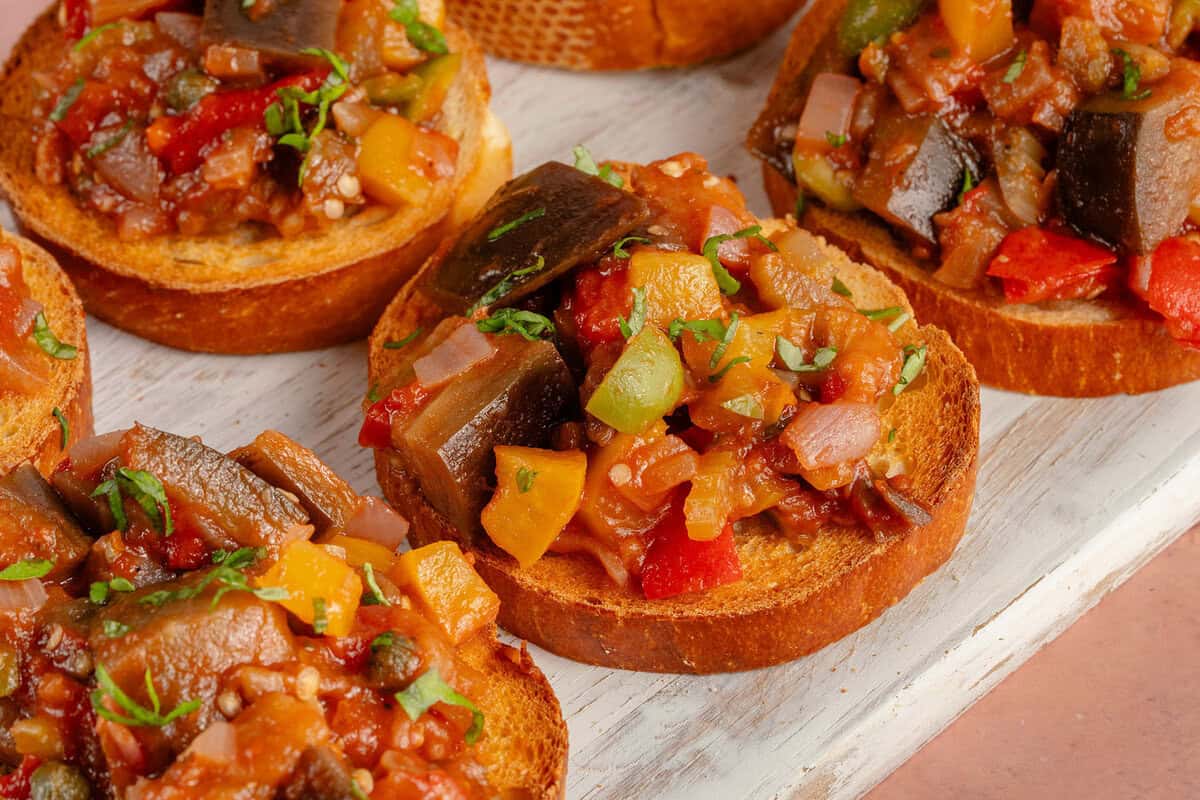 Eggplant Caponata on toasted bread on top of white serving tray