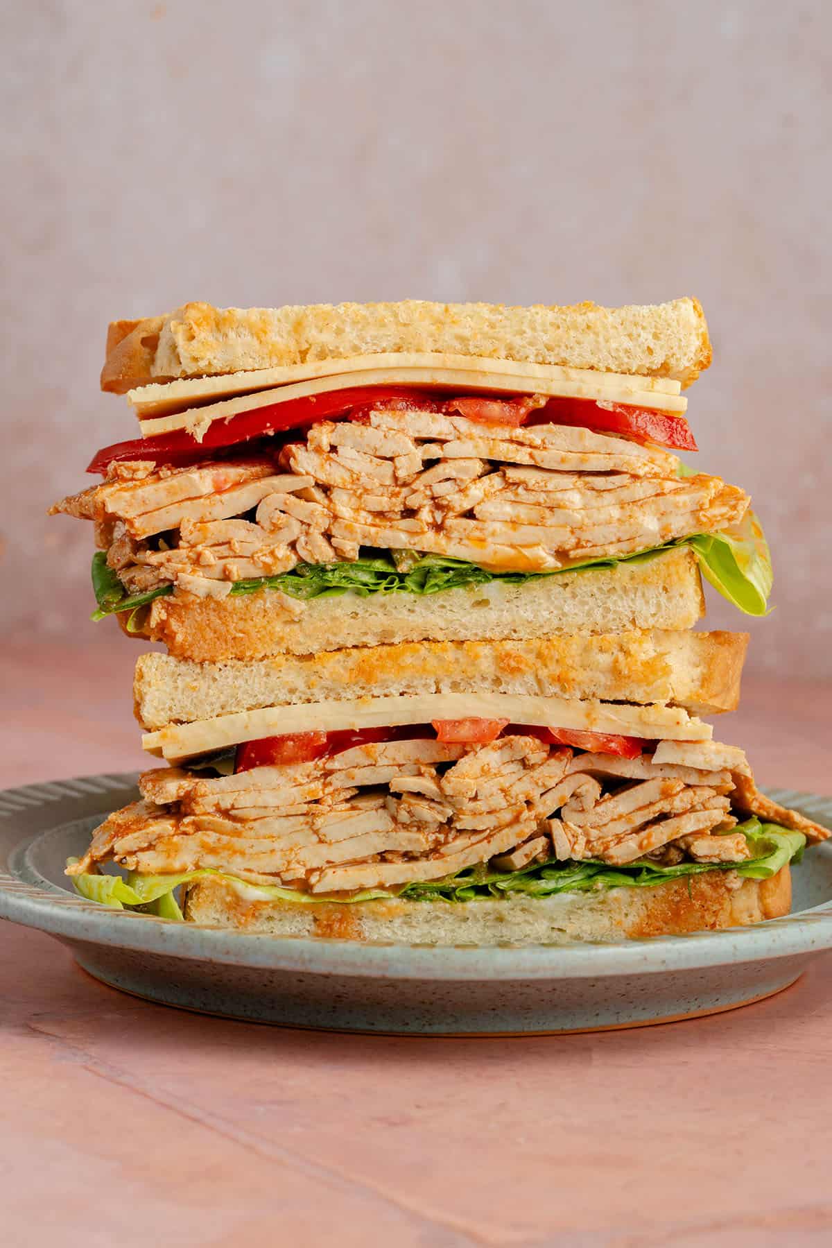 stacked sandwich with Ham-Style Tofu Deli Meat Slices, lettuce, tomato and vegan cheese