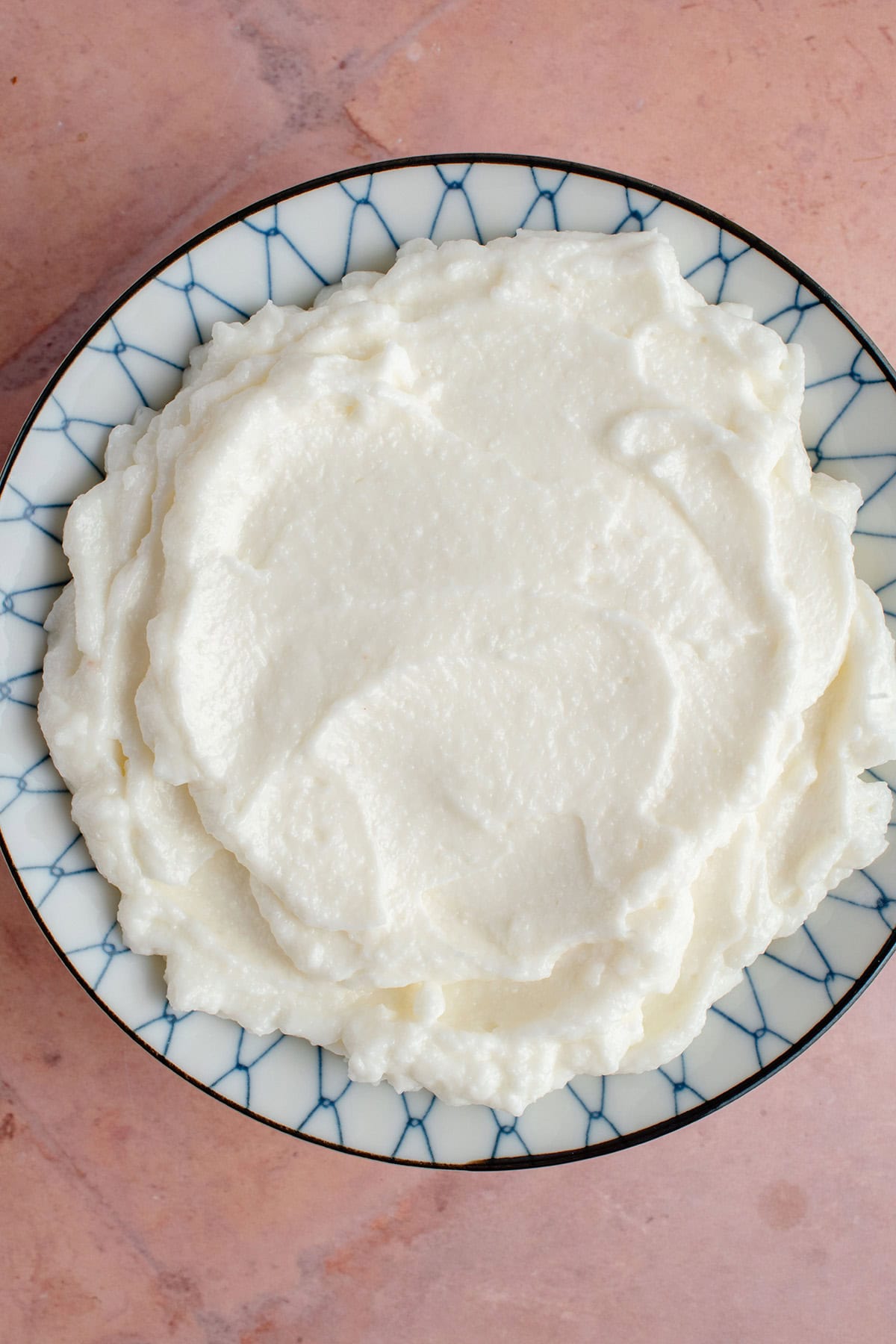 blue and white bowl of fresh Lebanese Garlic Sauce (Toum) on pink backdrop