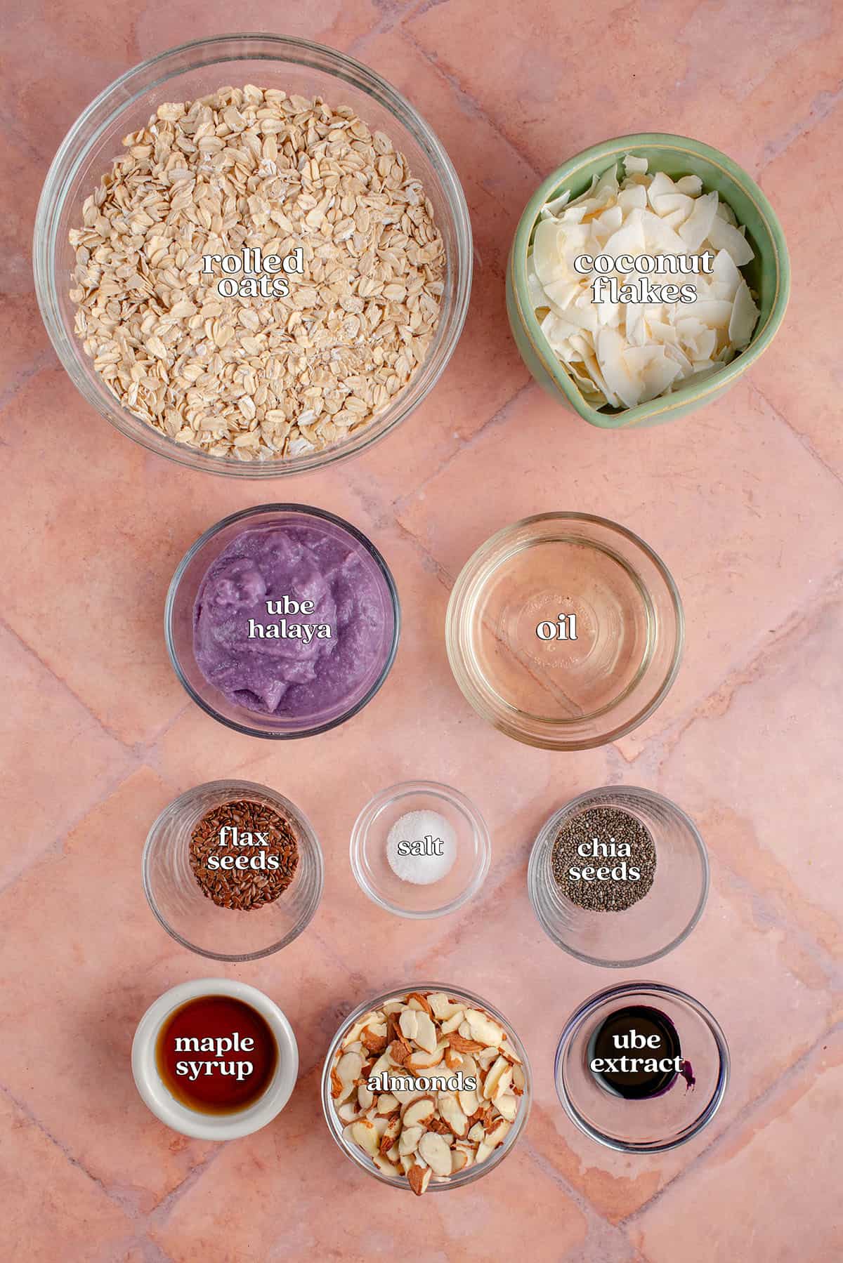 labeled ingredients for Ube Coconut Granola: rolled oats, coconut flakes, ube halaya, oil, flax seeds, salt, chia seeds, mape syrup, almonds and ube extract