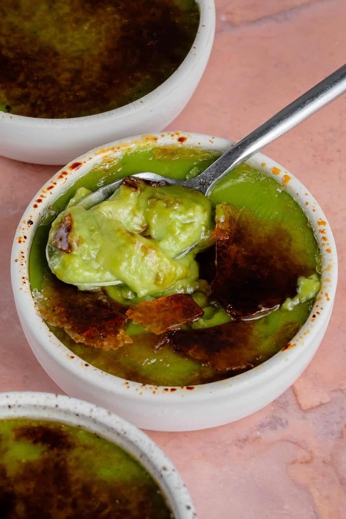 scooping out a spoon full of Vegan Matcha Crème Brûlée from white ramekin