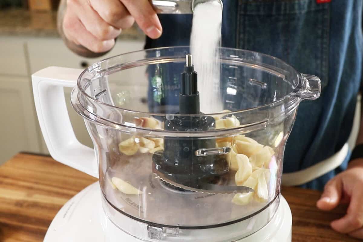 adding garlic and salt in food processor for Lebanese Garlic Sauce (Toum)