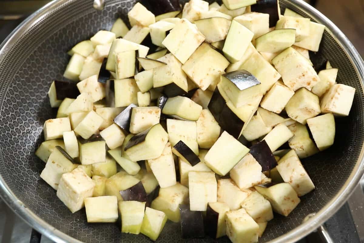 adding eggplant to a large wok for Eggplant Caponata