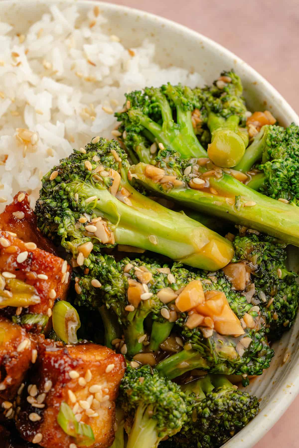 close up photo of 10-Minute Broccoli with Garlic Sauce in white bowl with rice and tofu