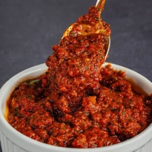 scooping Sun-Dried Tomato Pesto from white dish with spoon