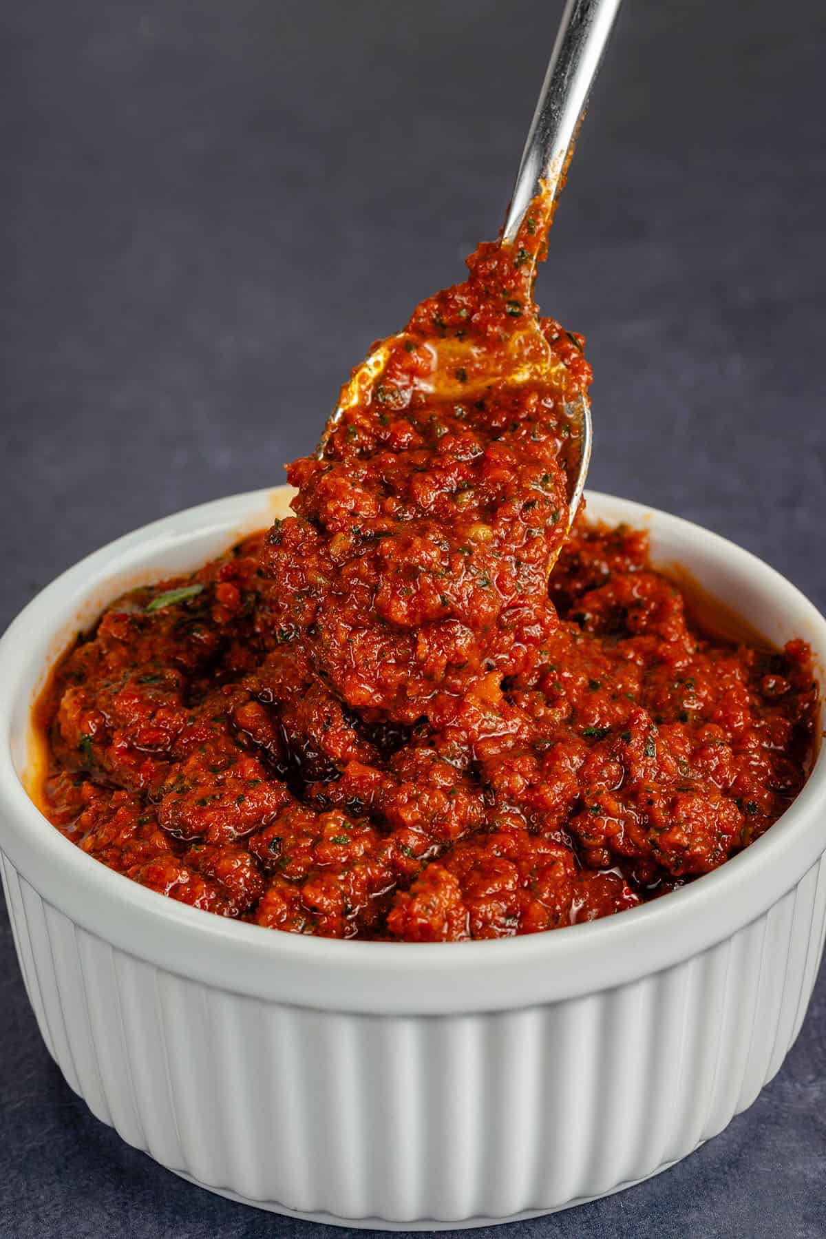 scooping Sun-Dried Tomato Pesto from white dish with spoon