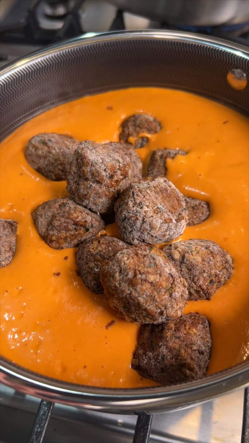 adding meatballs to sauce