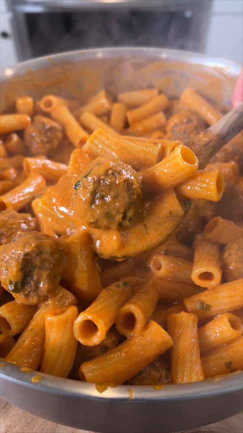 finished pasta with meatballs being scooped with a spoon