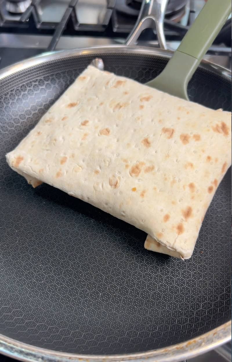 Folded lavash wrap being transferred to skillet