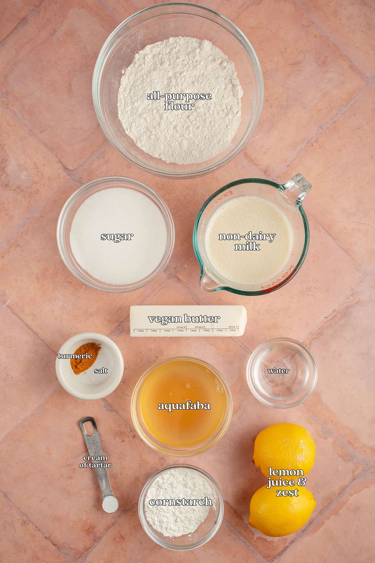 labeled ingredients for vegan lemon meringue pie: all-purpose flour, sugar, non-dairy milk, vegan butter, turmeric, salt, aquafaba, water, cream of tartar, cornstarch, lemon juice and zest