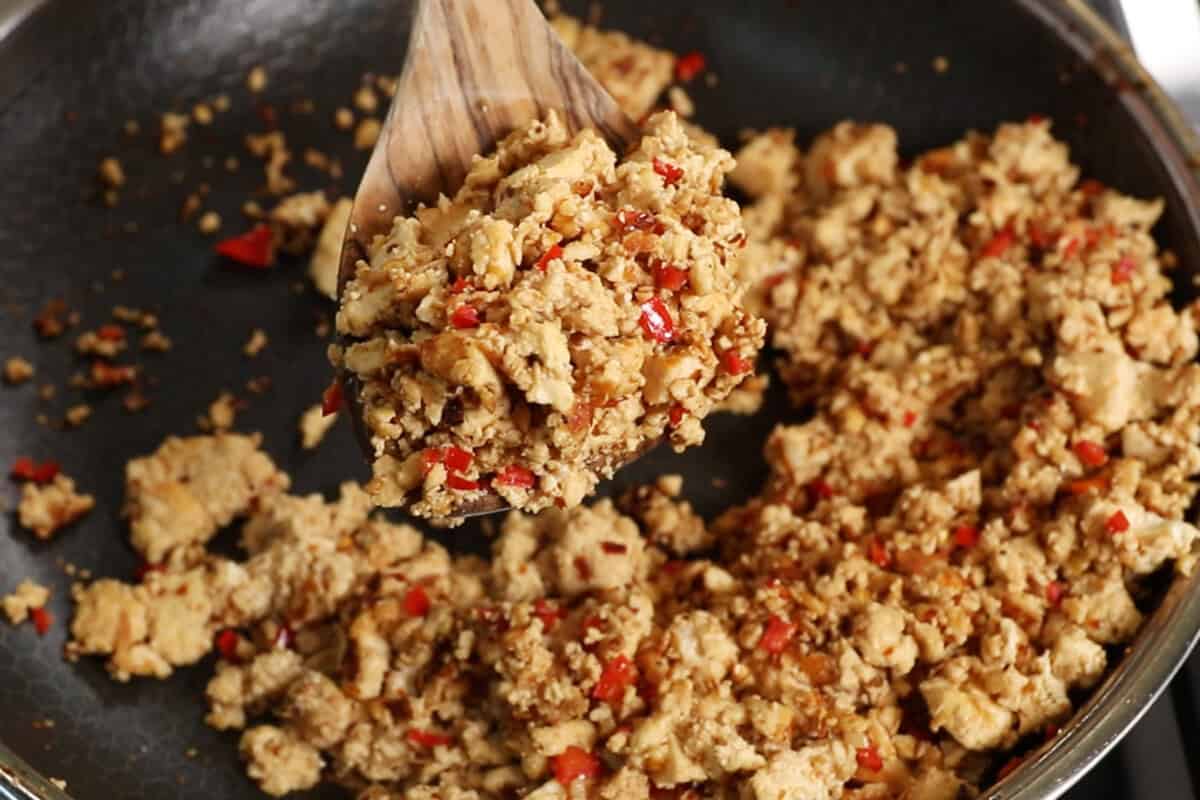finished chili lime tofu in a skillet being picked up with wooden spoon