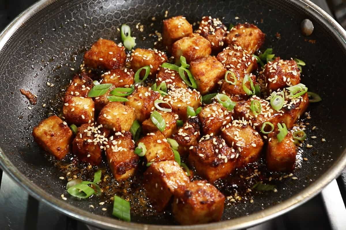 finished maple glazed tofu in a pan with sesame seeds and green onions