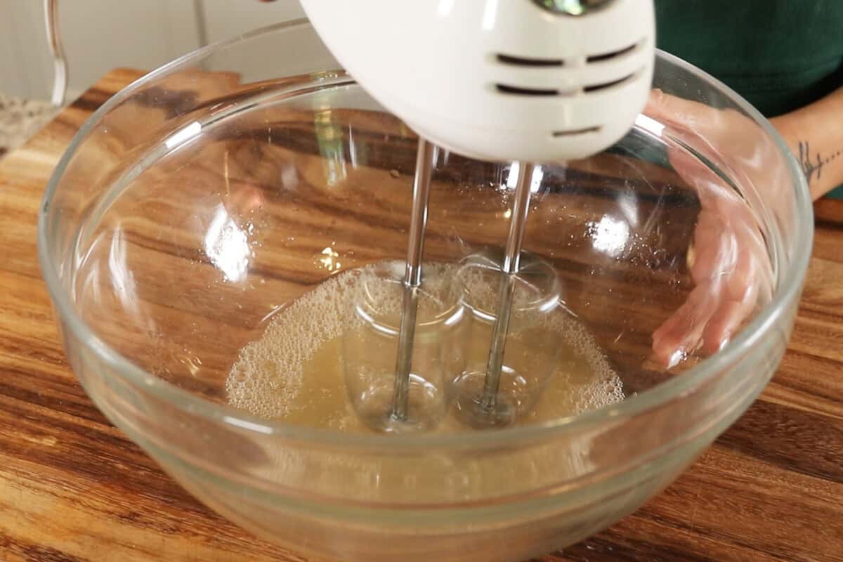 whipping aquafaba and cream of tartar in large glass bowl for vegan meringue
