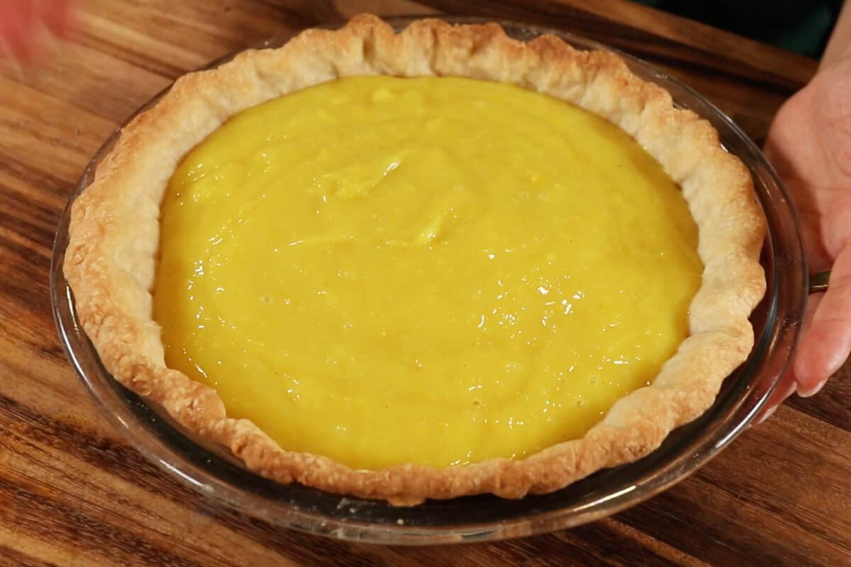 horizontal photo of a lemon curd pie filling in crust before setting in fridge