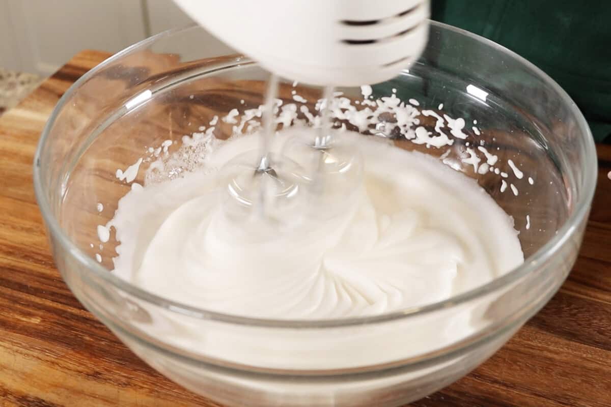 whipping aquafaba and cream of tartar in large glass bowl for vegan meringue
