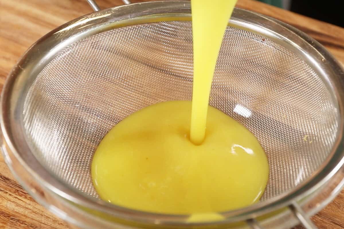 A person pouring lemon curd into a bowl.