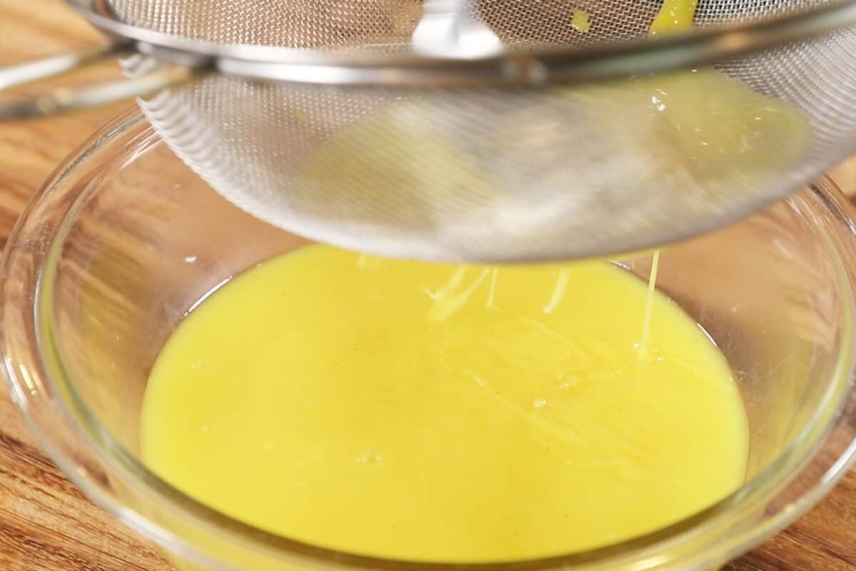 A strainer is being used to strain the lemon curd
