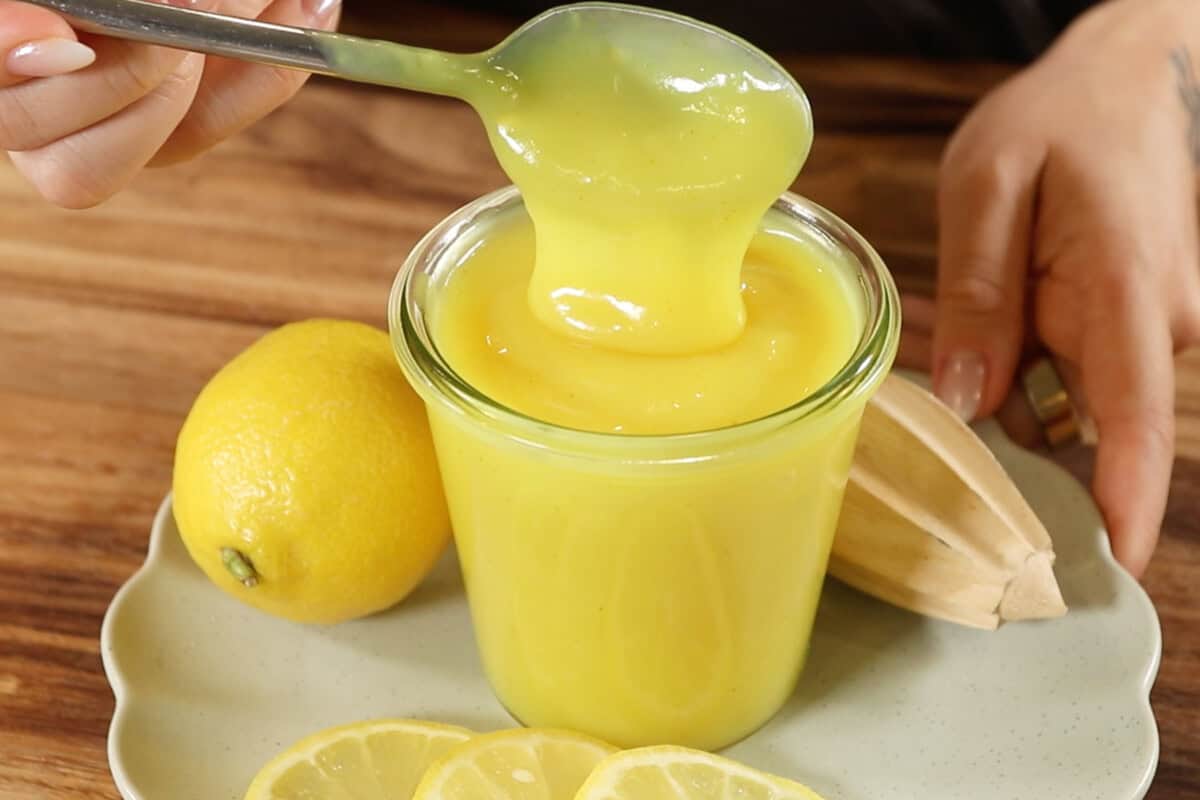 A person is holding a spoon over a jar of lemon juice.